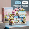 A boxed set of blue and pink micro building blocks depicting a storefront with flowers and a small display.