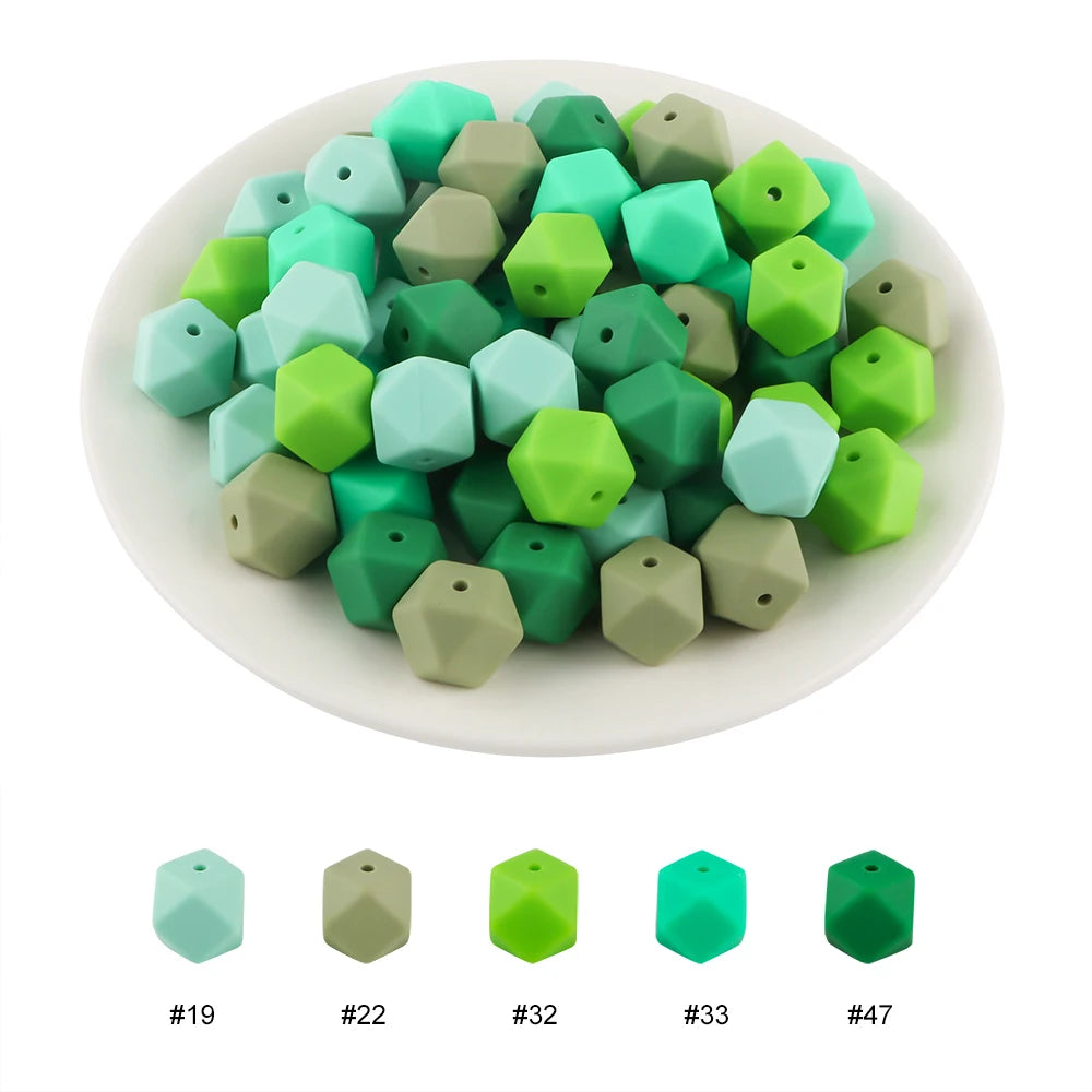 A collection of fifteen hexagonal silicone beads in various shades of green and gray arranged on a white plate.