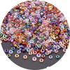 A close-up view of a pile of multi-colored glass rice beads in various sizes for DIY jewelry and crafting.