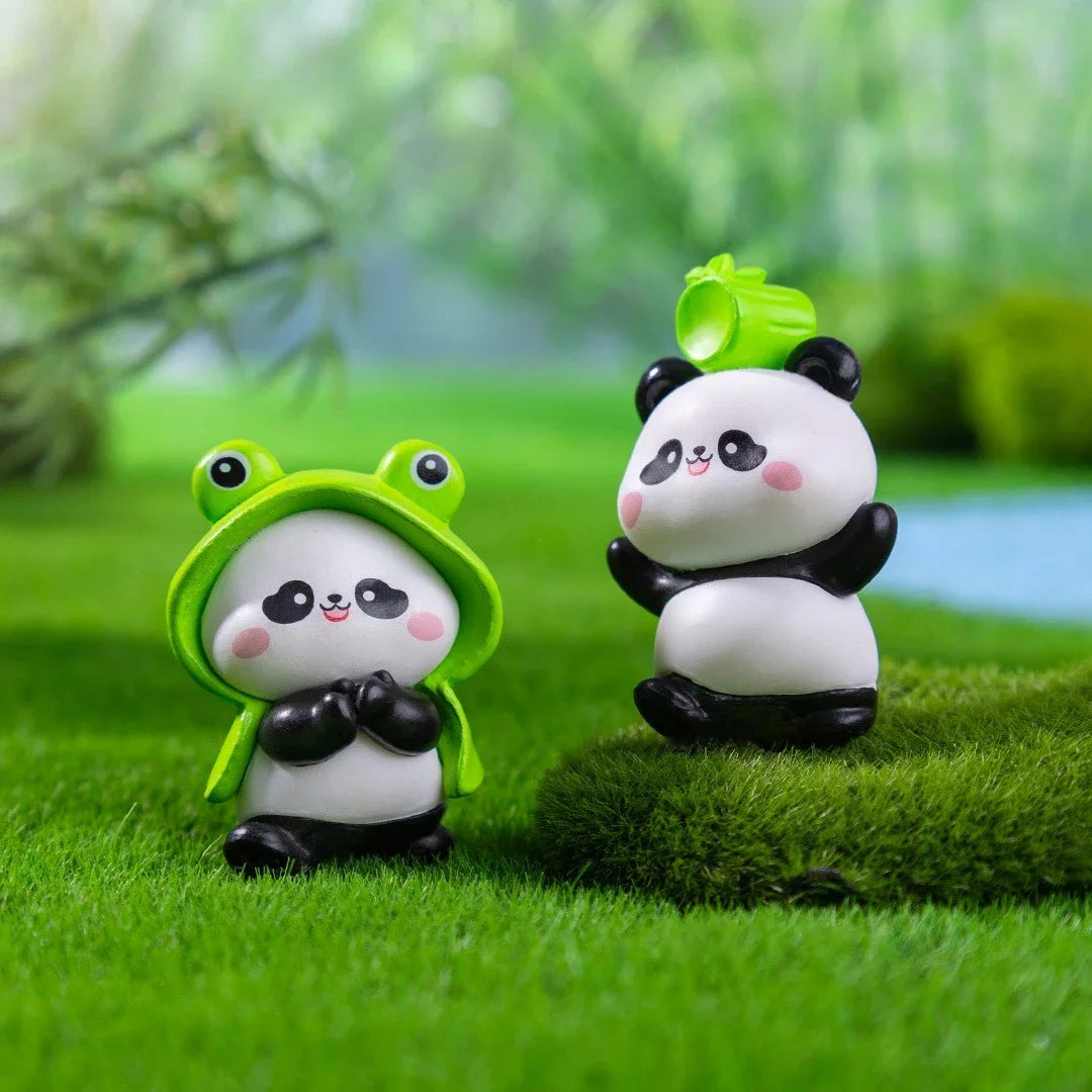 A set of adorable resin panda figurines, one with a green leaf and another in a green helmet, placed on green grass.