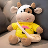 A yellow plush cow stuffed animal with white and black markings sitting on a light surface.