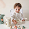 A toddler is playing with a set of wooden screws and matching toys on a table.