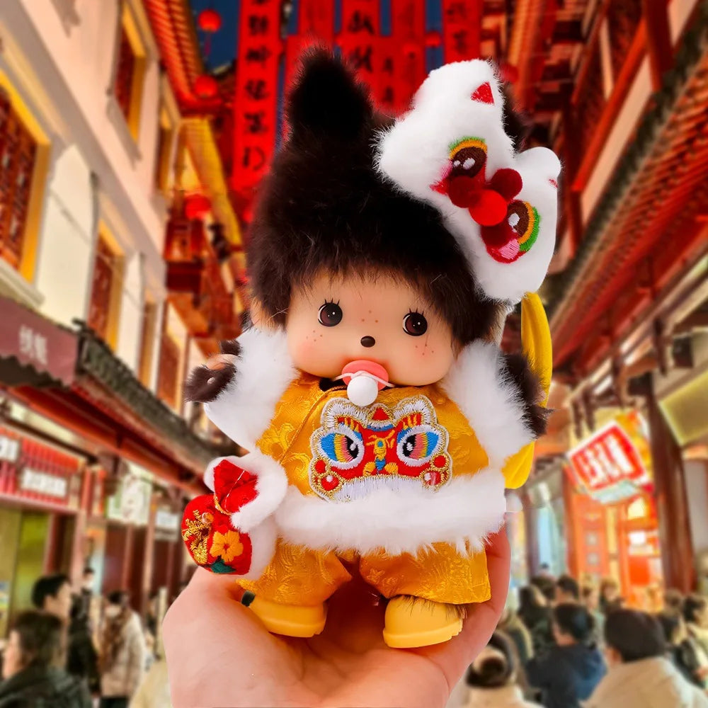 A cute Monchhichi plush keychain with black fur, white ears, and a yellow outfit being held up against a traditional Chinese 