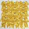 A pack of twelve gold glitter sequin pigtail bows for girls with elastic hair ties.