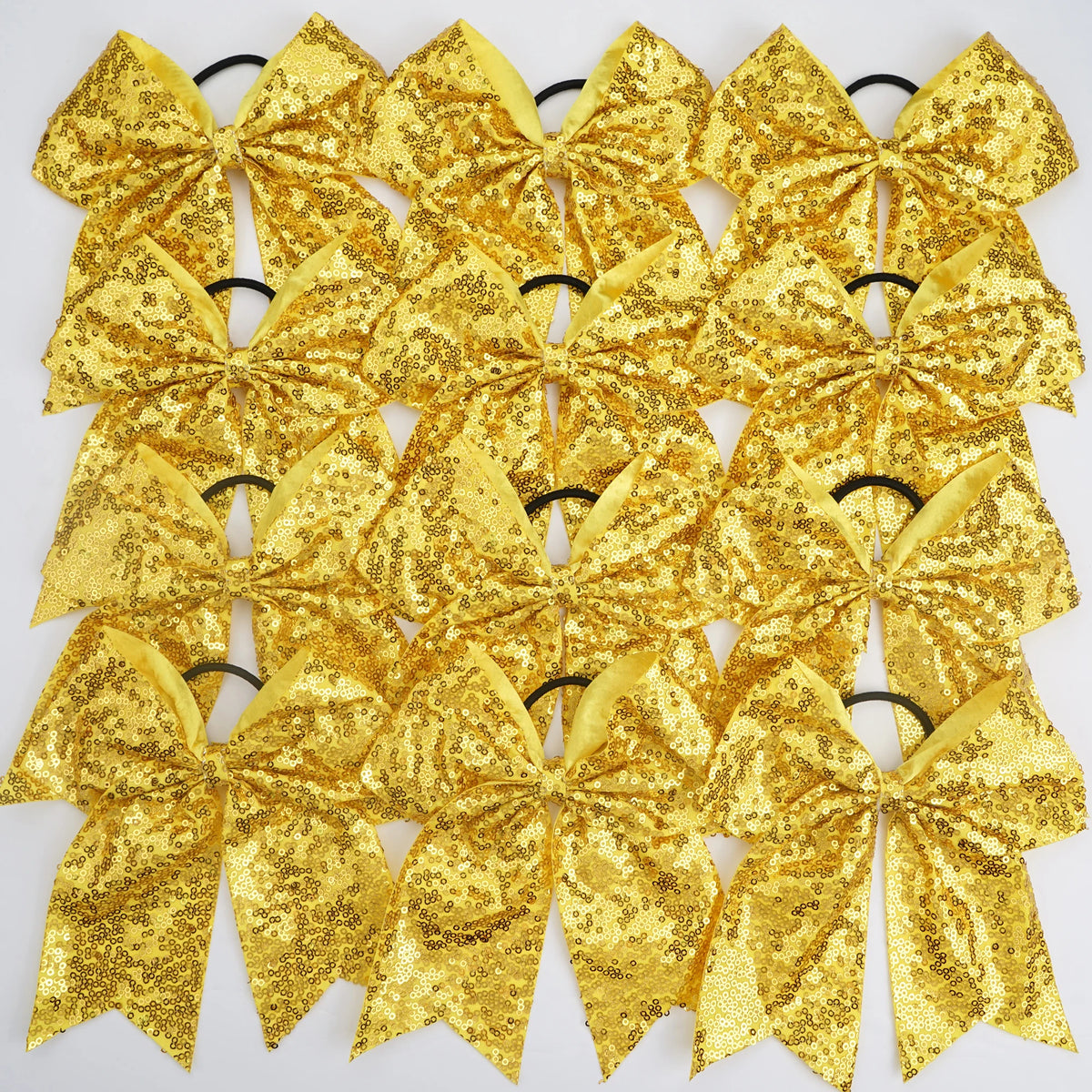 A pack of twelve gold glitter sequin pigtail bows for girls with elastic hair ties.
