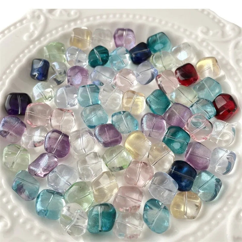 A pile of irregular square geometric glass beads in various shades of blue, purple, and pink.