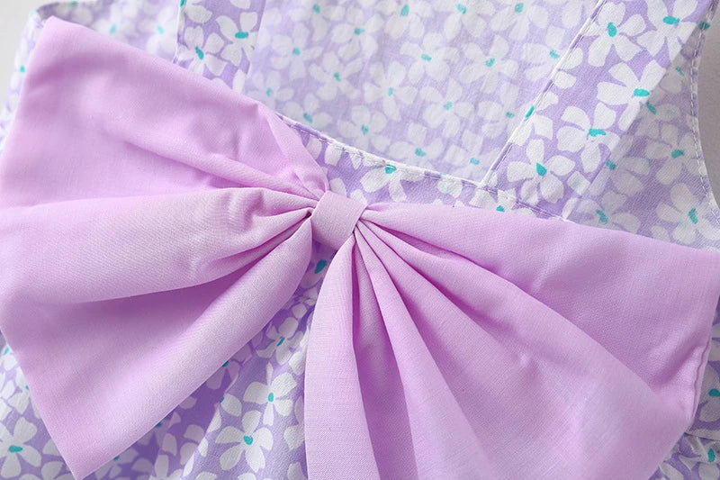 A lilac floral print dress featuring a pink bow detail and gathered fabric.