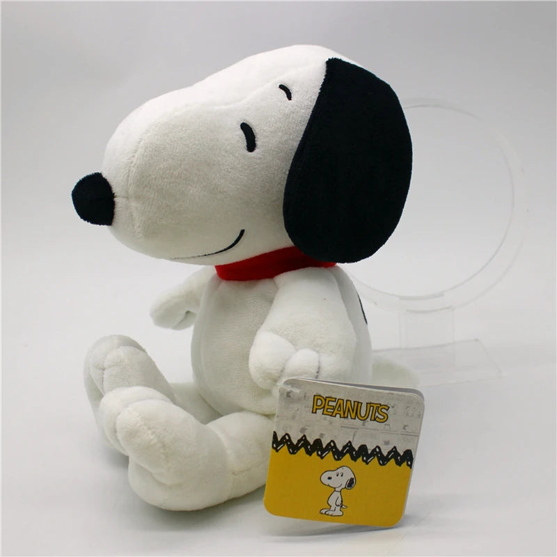 A white Snoopy plush toy with black ears and a red collar sitting on a clear stand.