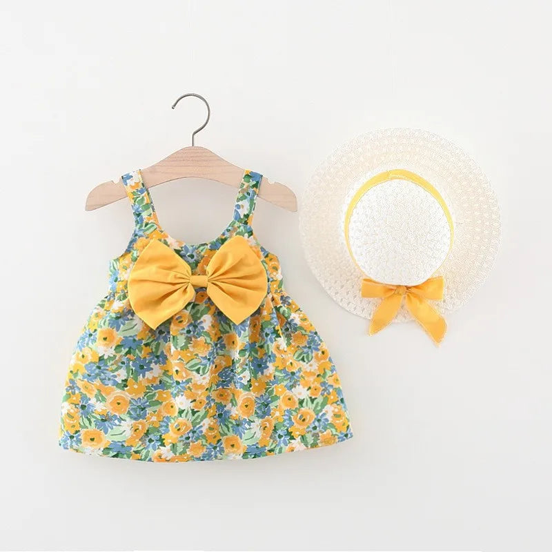 A yellow floral print baby girl summer dress with a matching yellow bow and a white sunhat