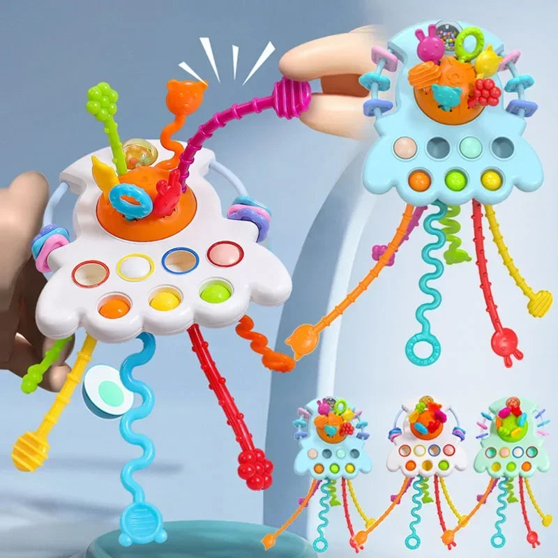 A hand is pulling colorful string toys with various shapes and colors from a white cloud-shaped sensory toy.