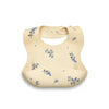 A beige soft silicone waterproof baby bib with an adjustable neck, featuring small blue floral patterns.