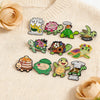 A set of cute green turtle enamel pins featuring various designs and sayings on a light sweater.
