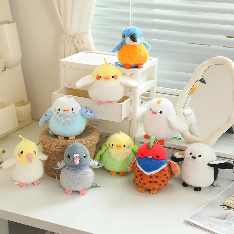 A collection of colorful cartoon bird plush keychains and pendants displayed on a white table.