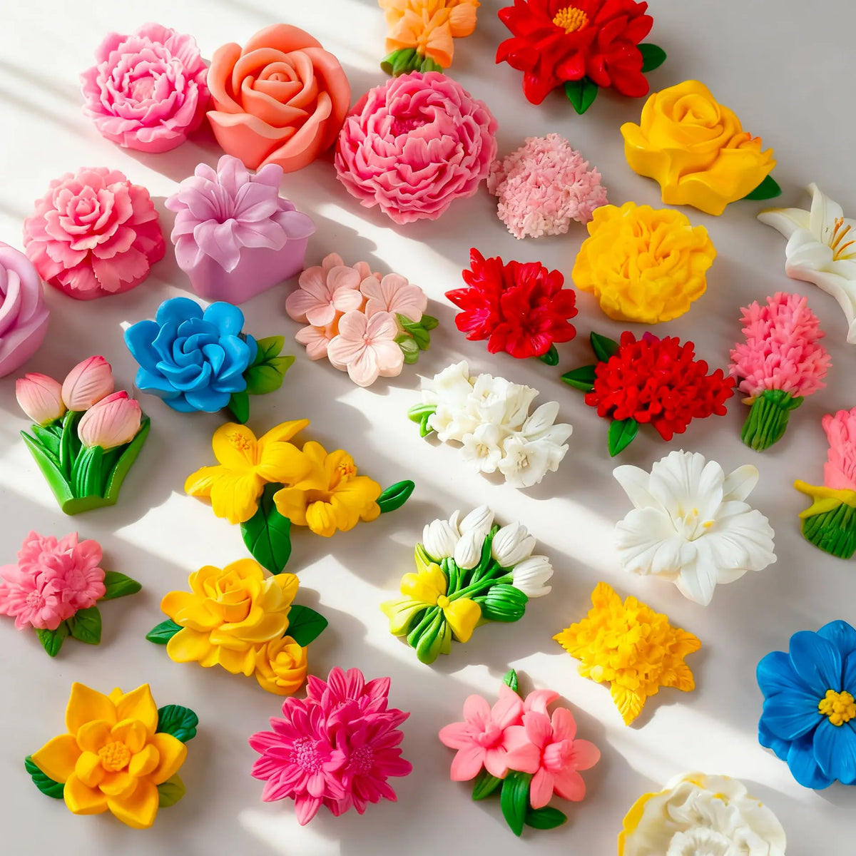A collection of multi-colored silicone flower molds in various shades of pink, orange, yellow, and red.