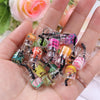 A hand holds a collection of 20 assorted resin fruit and drink charms for jewelry making.