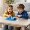 Two children play a blue strategy board game with white and black pieces on a wooden table.