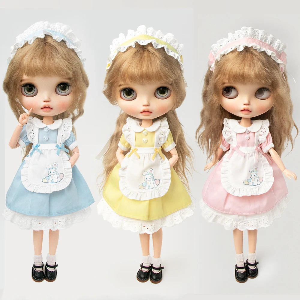 Three dolls wearing vintage lace maid dress sets in blue, yellow, and pink