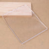 A clear silicone gel printing plate rests on a light wooden surface.