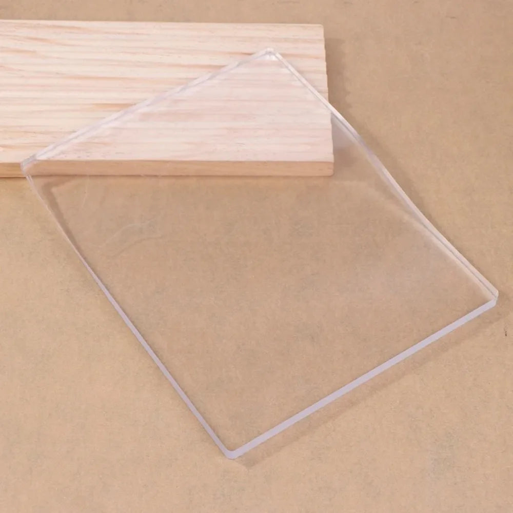 A clear silicone gel printing plate rests on a light wooden surface.