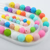 A variety of colorful soft silicone beads in various sizes are arranged on a white tray.