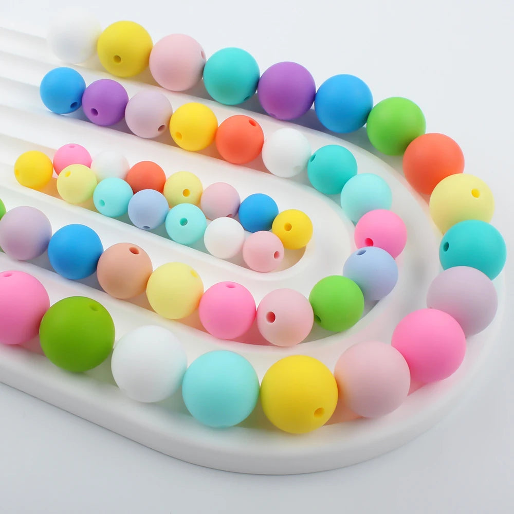 A variety of colorful soft silicone beads in various sizes are arranged on a white tray.