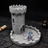 A gray medieval castle tower model with dice resting on a circular tray on a dark stone surface.
