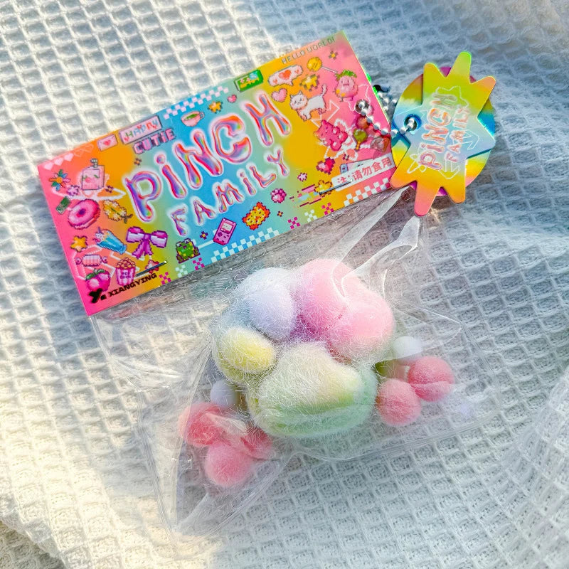 A pink and yellow packaged squishy toy featuring a cat paw design on a white textured surface.