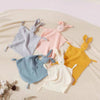 A collection of soft cotton muslin baby comforters in pastel colors, including lavender, pink, blue, yellow, and cream.