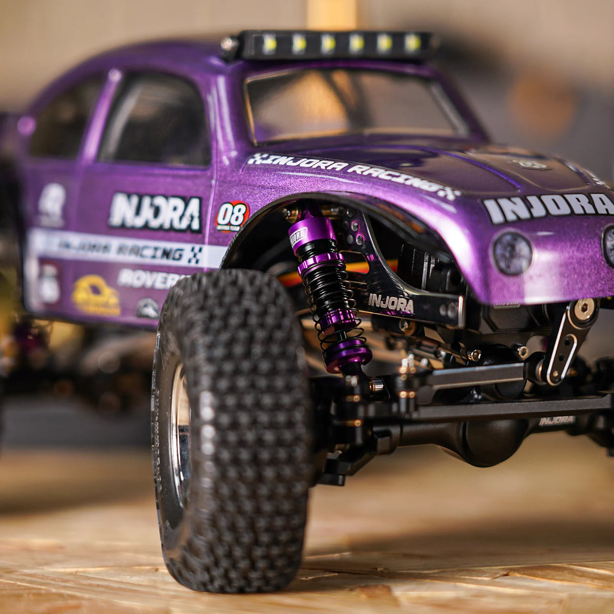Purple Injora racing buggy with heavy-duty oil shocks mounted on the chassis.