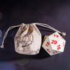 A beige drawstring bag with a handprint design and a white D20 polyhedral dice resting next to it.
