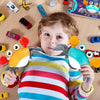 A toddler holds an orange and gray interactive crab toy with music and obstacle avoidance features.