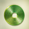 A bright green, textured ring with concentric grooves, designed as a kinetic desk toy.