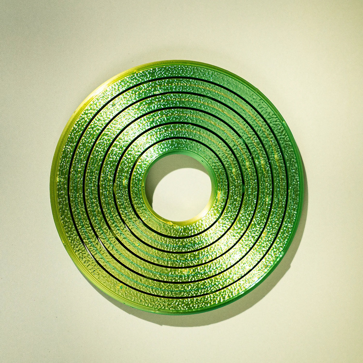 A bright green, textured ring with concentric grooves, designed as a kinetic desk toy.