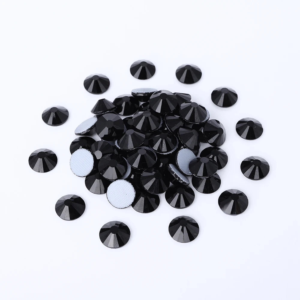A scattered pile of clear glass crystal hot fix rhinestones for DIY crafts and decor.