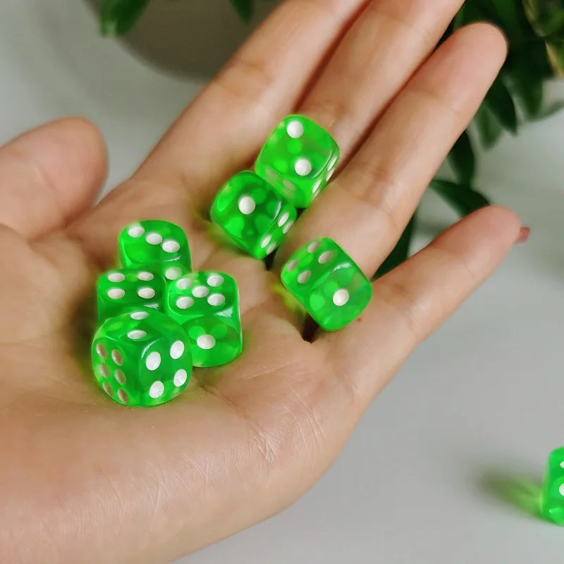 A hand holds several bright green transparent dice with white polka dots.