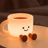 A glowing, cup-shaped night light with a smiling face is placed on a surface.