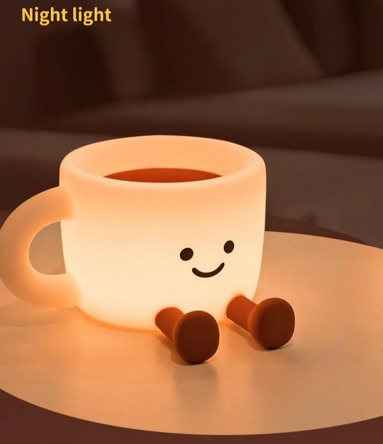 A glowing, cup-shaped night light with a smiling face is placed on a surface.