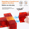 A hand holds a red magnetic building block cube, showing its transparent construction and interlocking shapes.