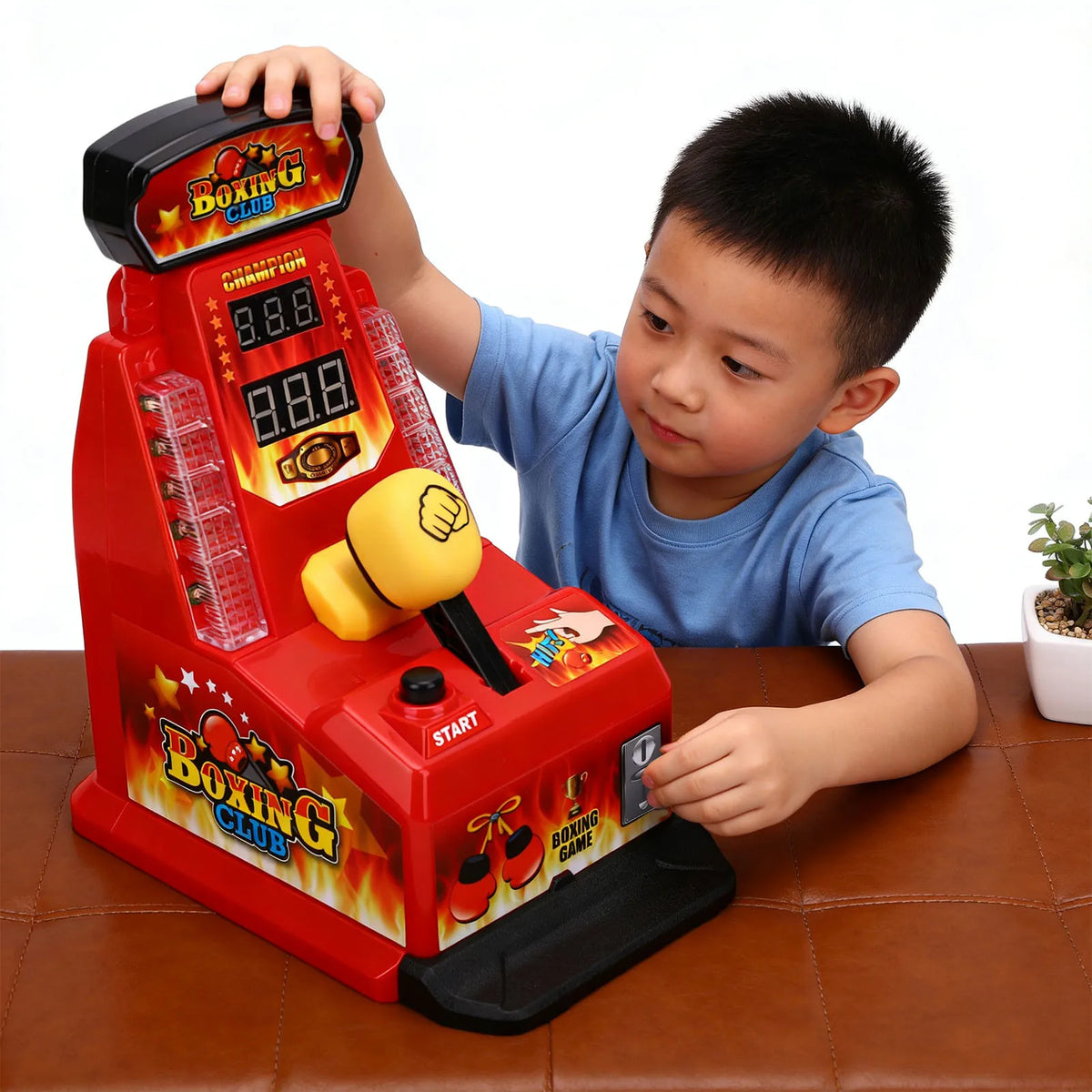 A young boy is playing an interactive finger boxing game machine with red and orange lights on a brown table.