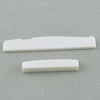 Two white guitar nut and bridge saddle components lying on a gray surface