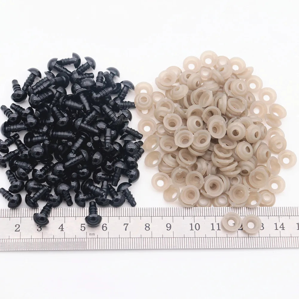 A collection of black and beige plastic safety eyes for amigurumi, measured against a ruler.