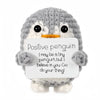 A handmade gray crochet penguin doll holding a card that says Positive penguin I may be a tiny penguin but I believe in you G