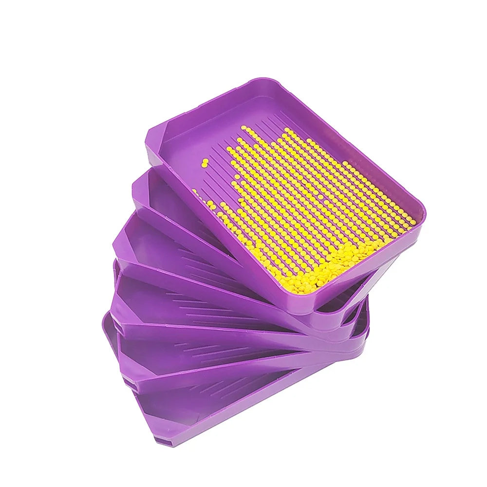 A purple diamond painting tool kit with a tray filled with yellow beads, including a pen and tweezers.