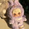 A purple fluffy plush doll with large ears and a facial feature resembling a baby face is shown.