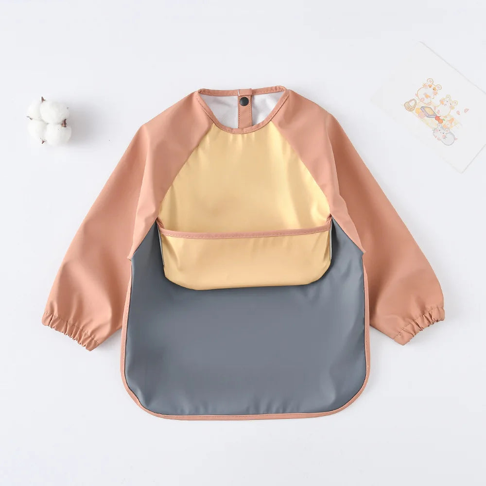 A light peach and yellow waterproof long-sleeved baby bib with a gray absorbent section.