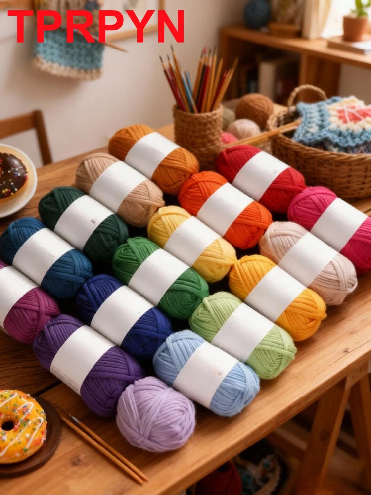 A pile of soft chunky t-shirt yarn in various colors, including orange, pink, green, and purple, laid out on a wooden table.