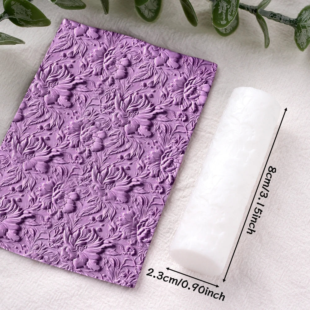 A roll of purple floral and leaf clay texture rollers resting on a white cloth.