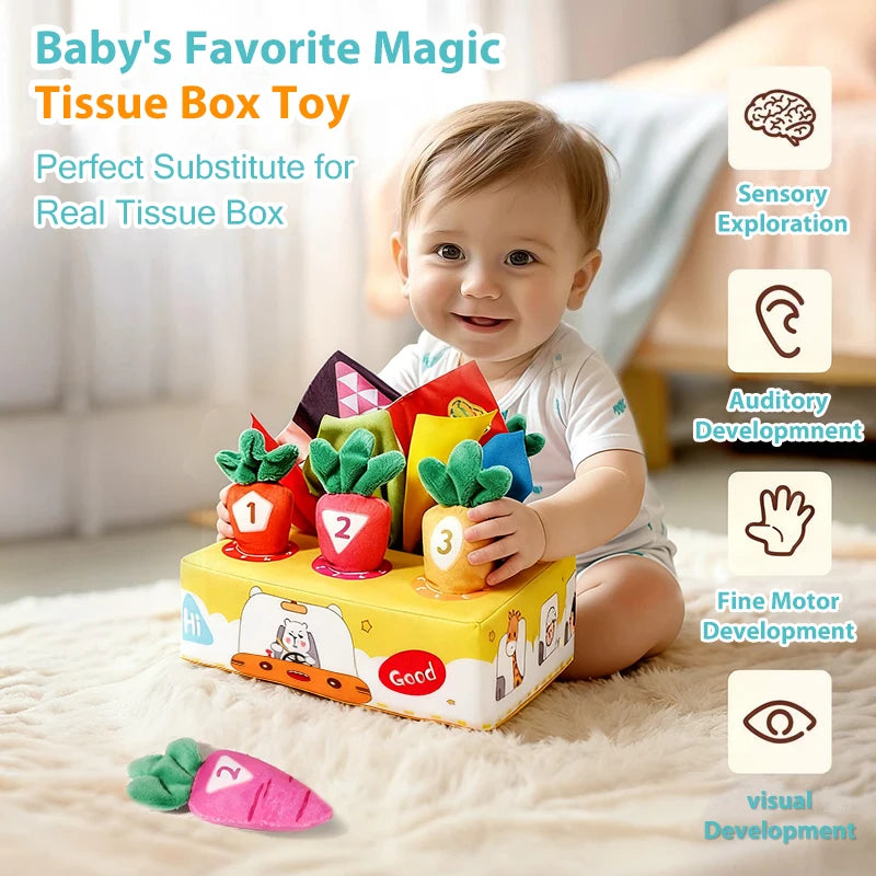 A baby is interacting with a colorful tissue box toy featuring carrot-shaped sensory items for fine motor and sensory explora
