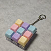 A clear plastic container filled with colorful fidget cubes and a silver keychain.