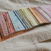 A collection of rainbow textured paper sheets in various shades and patterns laid out on a light fabric.